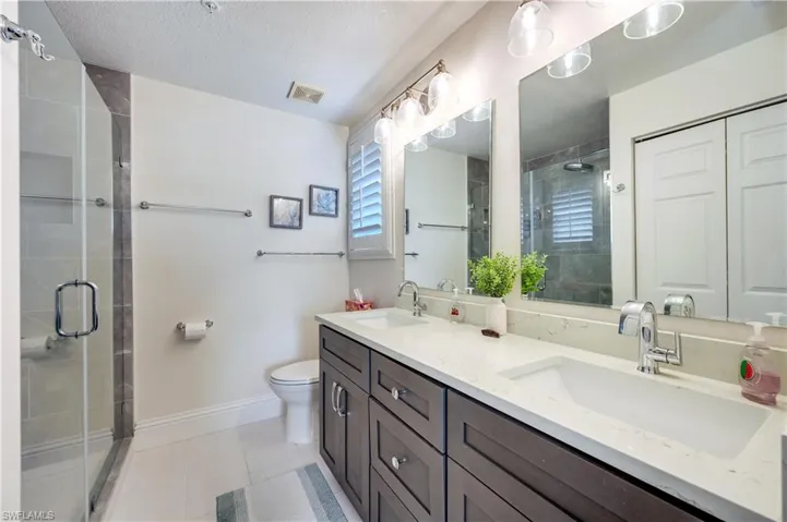 Full bath featuring double vanity, a stall shower, and light tile patterned floors