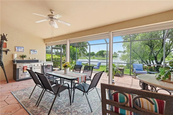 Screened patio featuring an outdoor kitchen with an integrated grill, a ceiling fan, and direct water frontage