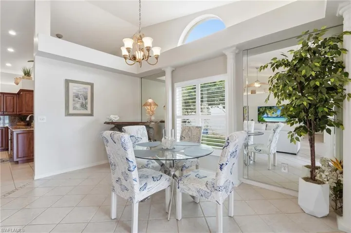 Dining area featuring tile flooring, a decorative chandelier, and a large window with white plantation shutters