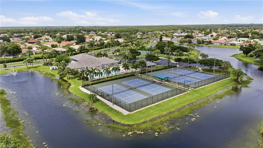 Aerial view showcasing the community clubhouse, multiple tennis courts, and surrounding waterways