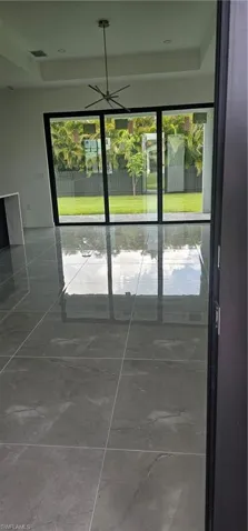 Doorway to outside with healthy amount of natural light, marble look tile flooring, and a raised ceiling