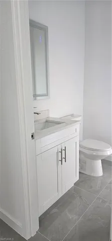 Half bathroom featuring vanity and dark marble finish floors