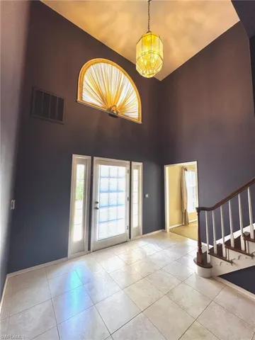Entrance foyer with light tile patterned floors, a chandelier, a high ceiling, and stairway