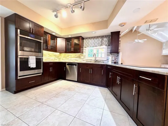 Kitchen featuring stainless steel appliances, decorative backsplash, ceiling fan, light tile patterned floors, and light countertops