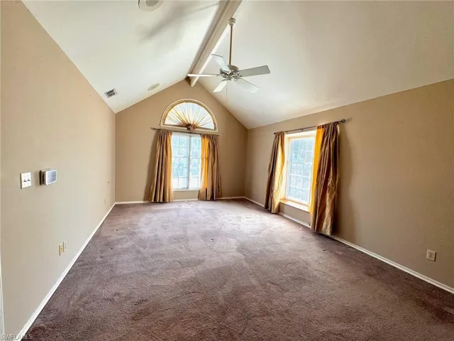 Primary Bedroom featuring high ceilings , ceiling fan, carpet floors, and a vaulted ceiling with beams