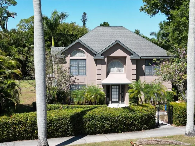 View of front facade with a shingled roof, a gate, and stucco siding