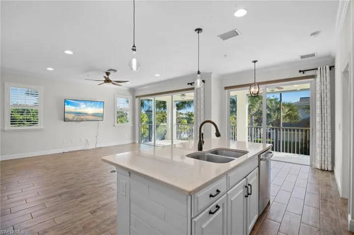 Kitchen featuring white cabinets, wood finish floors, light stone countertops, pendant lighting, and recessed lighting