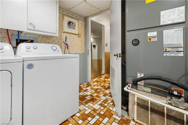 Laundry room featuring heating utilities, washing machine and clothes dryer, cabinets, and light tile floors