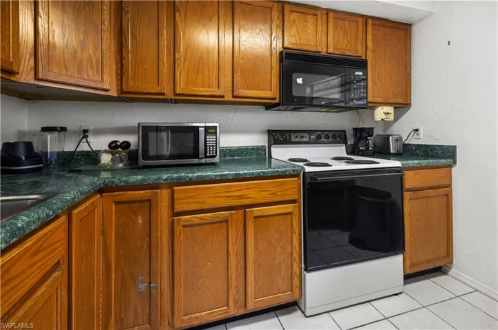 Kitchen with electric range and light tile floors in apartment