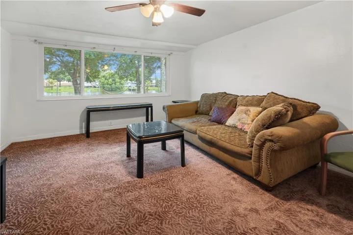 Carpeted living room featuring plenty of natural light and ceiling fan