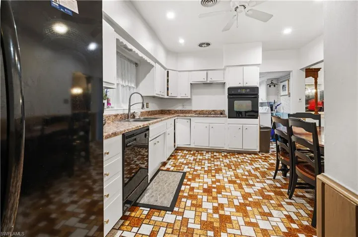 Kitchen featuring black appliances, sink, white cabinets, and ceiling fan