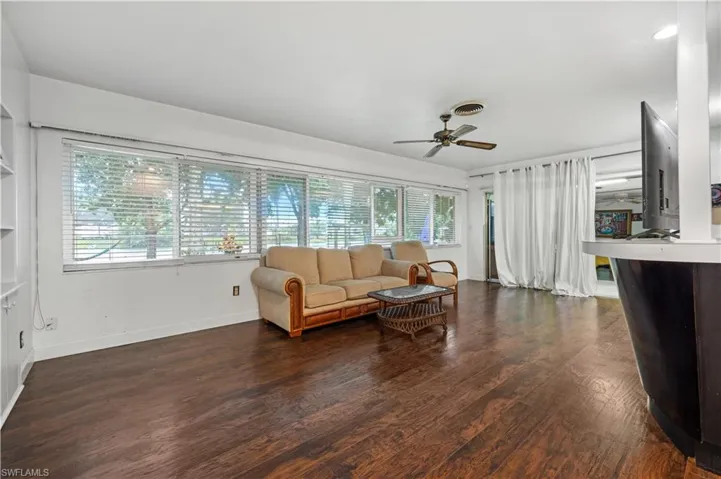 Living room with a wealth of natural light, dark wood-type flooring, and ceiling fan