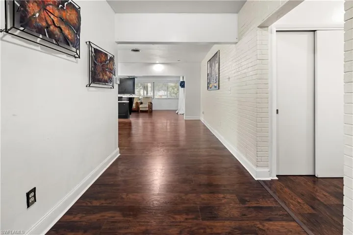 Hallway featuring dark hardwood / wood-style floors and brick wall
