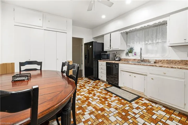Kitchen featuring white cabinetry, black appliances, sink, and ceiling fan