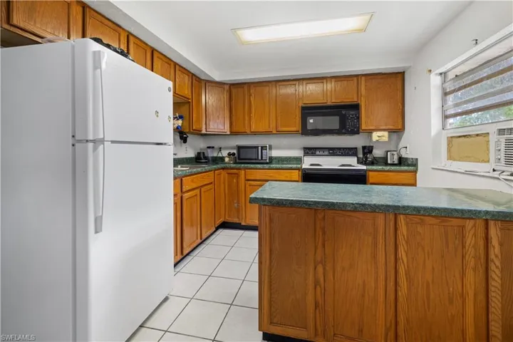 Kitchen featuring white appliances and light tile flooring in apartment