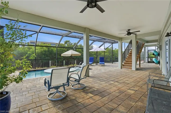 View of patio / terrace featuring stairway, ceiling fan, glass enclosure, and a sunroom - Virtually Edited Image