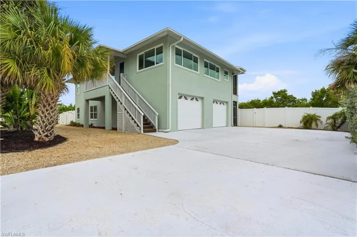 View of front of house with stairs, a garage, stucco siding, concrete driveway, and a gate - Virtually Edited Image