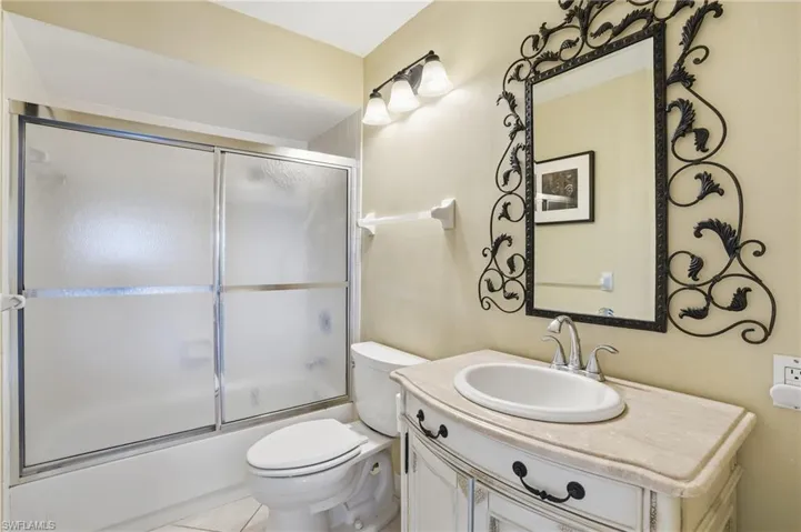 Bathroom featuring bath / shower combo with glass door, vanity, and light tile patterned floors - Virtually Edited Image