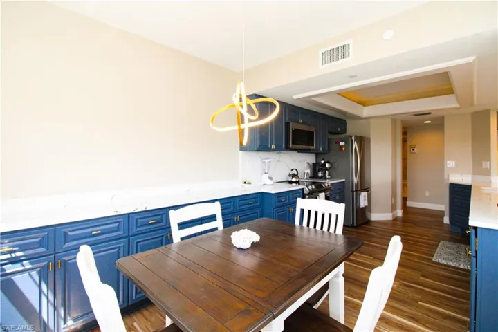 Dining room featuring a raised ceiling, an inviting chandelier, and dark hardwood / wood-style floors