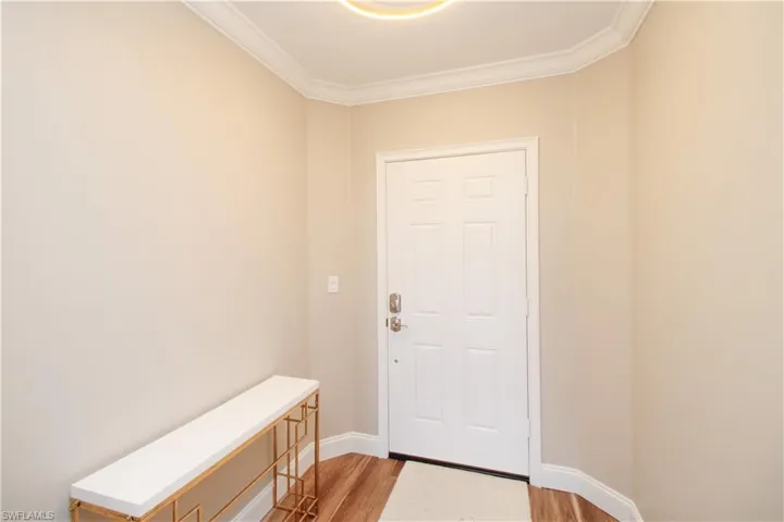 Entryway with light hardwood / wood-style flooring and crown molding