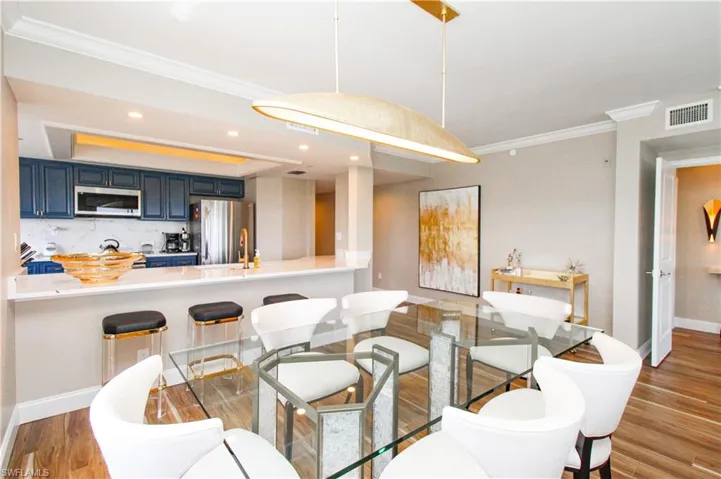 Dining area with ornamental molding and wood-type flooring