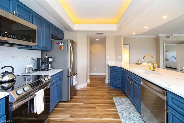 Kitchen with light hardwood / wood-style floors, crown molding, blue cabinets, and stainless steel appliances