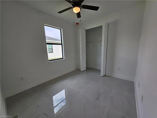 Unfurnished bedroom featuring light tile patterned floors, ceiling fan, and a closet