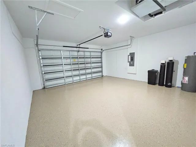 Garage with a garage door opener, water heater, and electric panel