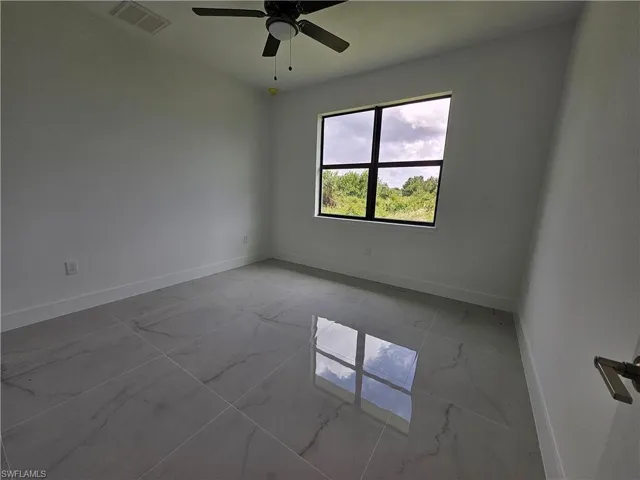 Tiled spare room featuring ceiling fan