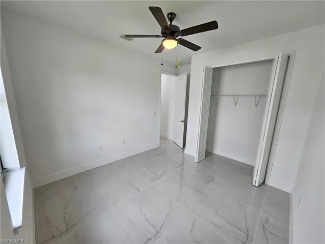 Unfurnished bedroom with light tile patterned floors, ceiling fan, and a closet