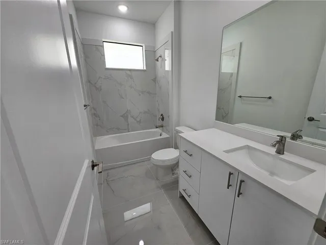 Full bathroom with toilet, tiled shower / bath combo, vanity, and tile patterned floors