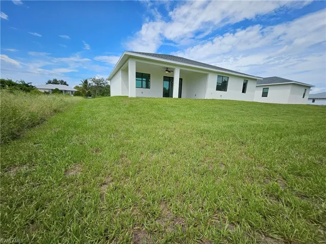 Back of house featuring ceiling fan and a lawn