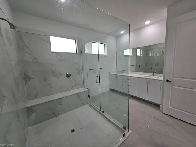 Bathroom featuring tile patterned floors, vanity, and walk in shower