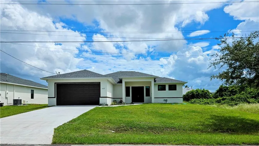 View of front of house with a garage, central air condition unit, and a front lawn