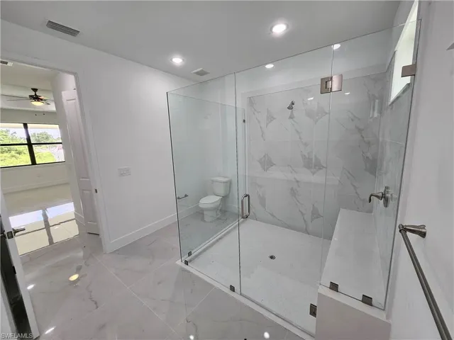 Bathroom with ceiling fan, tile patterned floors, toilet, and an enclosed shower