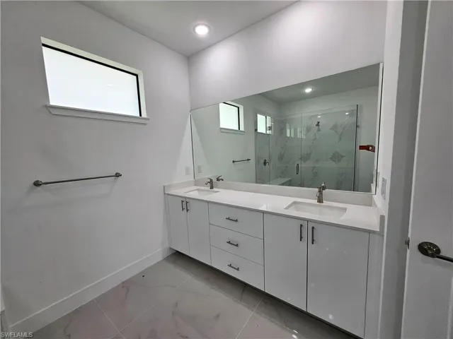 Bathroom with tile patterned flooring, a shower with door, and vanity