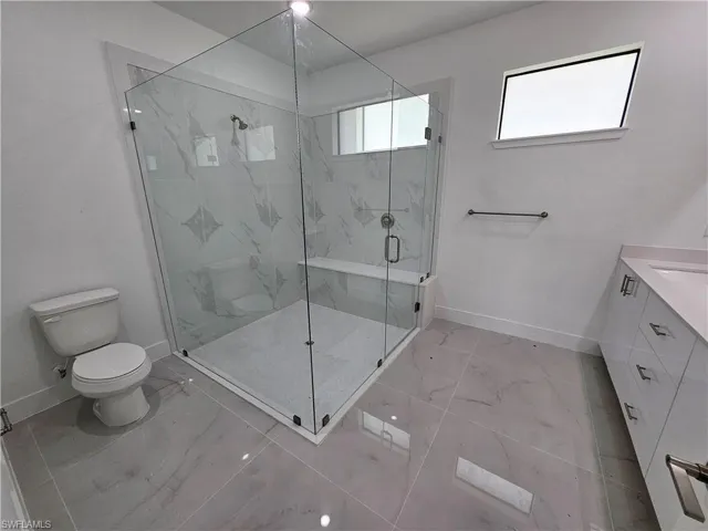 Bathroom featuring toilet, an enclosed shower, tile patterned flooring, and vanity