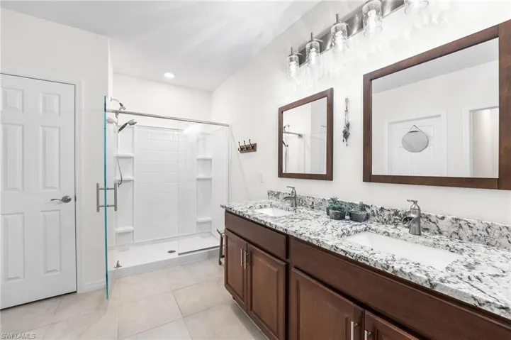 Bathroom featuring tile patterned floors, vanity, and an enclosed shower