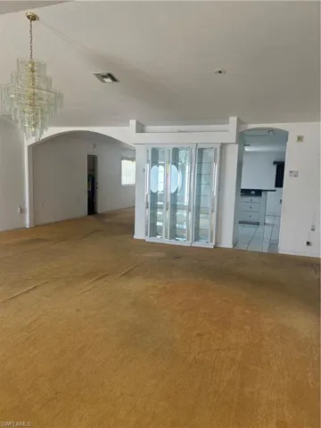 Unfurnished living room with a chandelier and light colored carpet