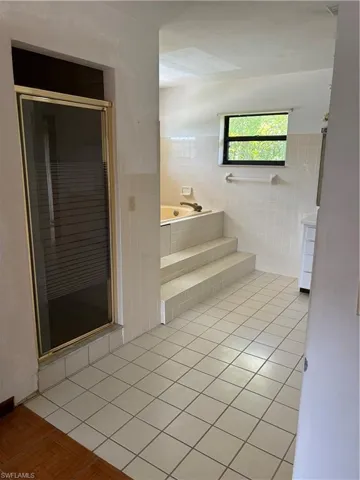 Bathroom with tile walls, tiled tub, and tile patterned floors