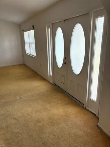 Carpeted entrance foyer with french doors