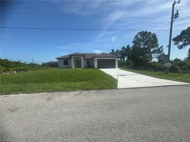 View of front of property with a garage and a front lawn