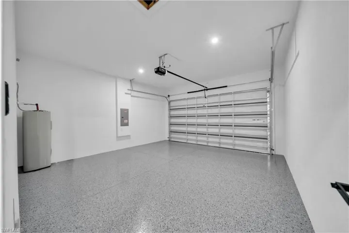 Spacious garage featuring a roll-up door, automatic opener, recessed lighting, and a textured epoxy floor finish