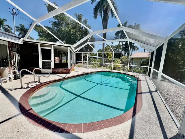 Outdoor pool featuring screen enclosure and a patio area