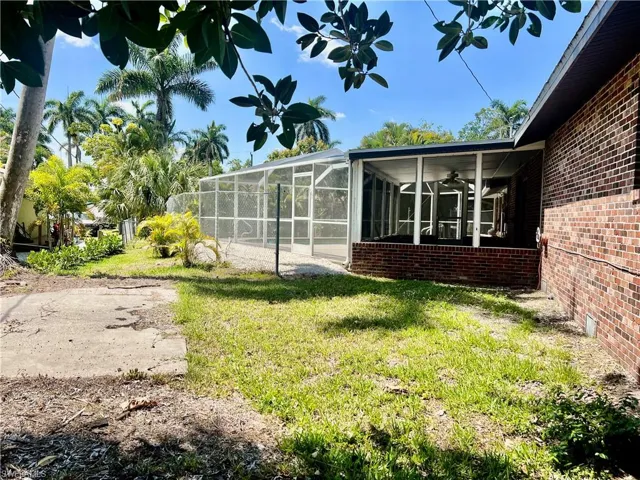 View of side of home with screen enclosure, a lawn, and ceiling fan