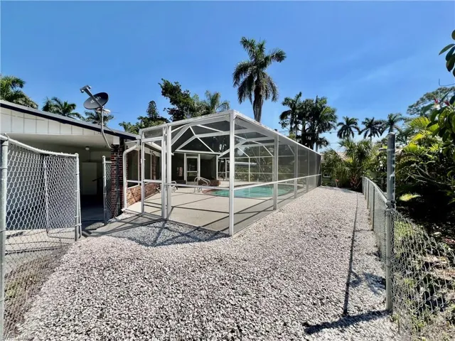Rear view of property with an outdoor pool, a patio area, a lanai, and a fenced backyard