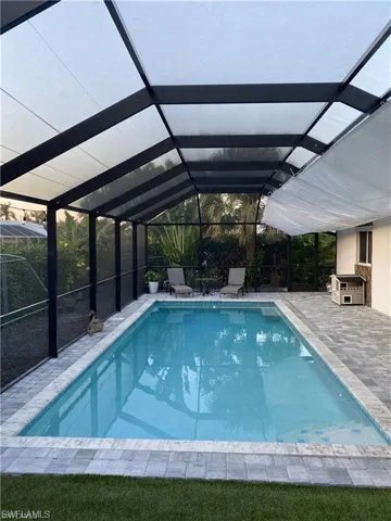 Swimming pool featuring a sunroom, a lanai, and a patio area