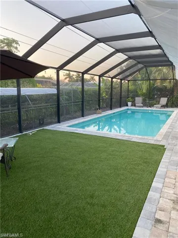 Swimming pool with a lanai, a lawn, a sunroom, and a patio area