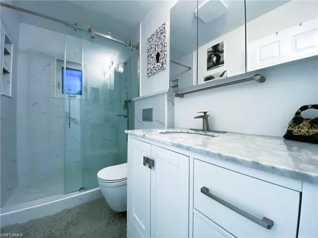 Bathroom with vanity and a marble finish shower
