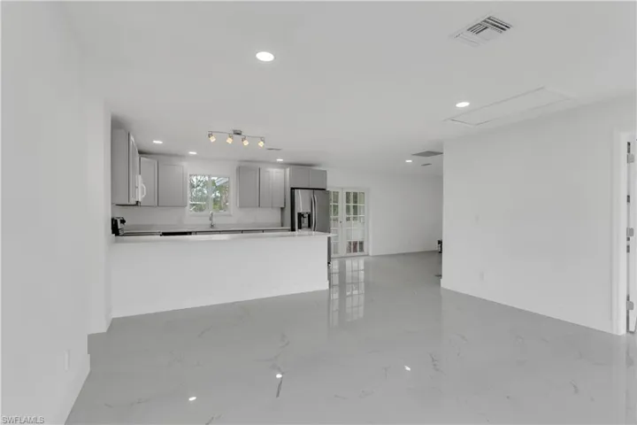 Kitchen featuring gray cabinets, sink, stainless steel refrigerator with ice dispenser, and kitchen peninsula